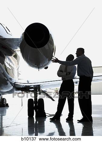 Two businessmen looking at a jet engine on an airplane View Large Photo Image Stock Photo - Two businessmen looking at a jet engine on an airplane. Fotosearch