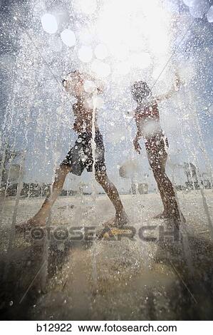 Stock Image - Two children playing at a sprayground. Fotosearch