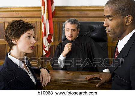 Two lawyers standing face to face in front of a male judge in a courtroom View Large Photo Image Stock Image - Two lawyers standing face to face in front of a male judge in a courtroom. Fotosearch