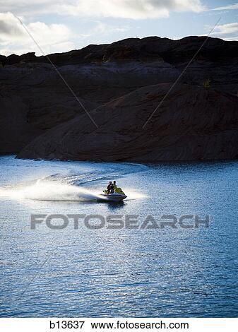 Stock Photo - Two people on personal water craft with rock formations. Fotosearch