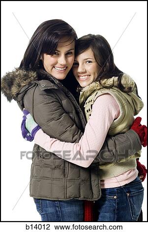 Stock Image - Two women hugging and smiling with winter coats. Fotosearch