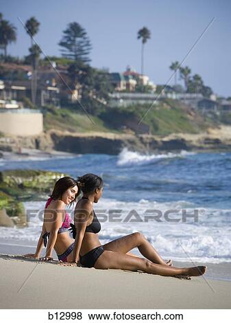 Two women relaxing on a beach View Large Photo Image Stock Photo - Two women relaxing on a beach. Fotosearch