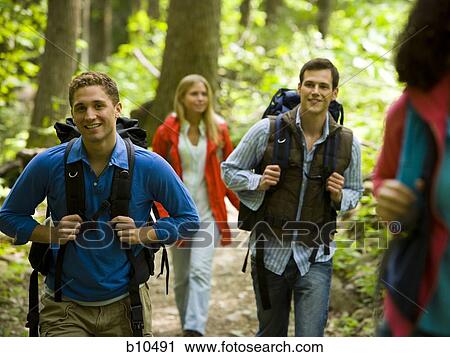 Stock Image - Two young women and two young men walking in the forest. Fotosearch