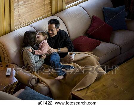 Woman and man snuggling with young girl on sofa View Large Photo Image Stock Image - Woman and man snuggling with young girl on sofa. Fotosearch