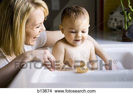 Picture - Woman bathing baby in sink. Fotosearch