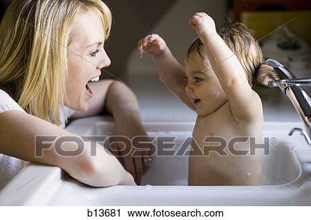 Stock Image - Woman bathing baby in sink. Fotosearch