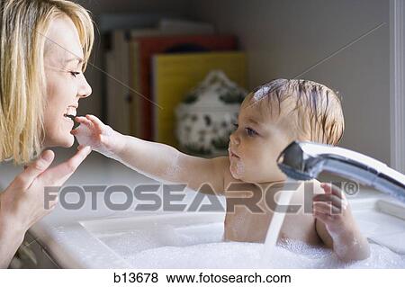 Woman bathing baby in sink View Large Photo Image Stock Photo - Woman bathing baby in sink. Fotosearch