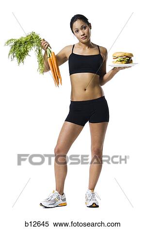 Woman choosing between carrots or hamburger View Large Photo Image Stock Photography - Woman choosing between carrots or hamburger. Fotosearch