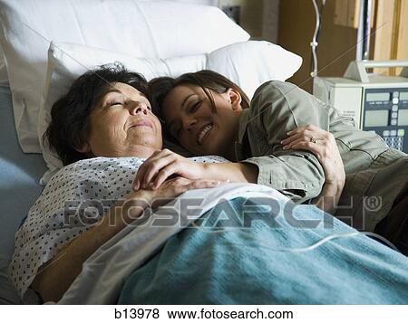 Woman cuddling in hospital bed with mature woman smiling View Large Photo Image Stock Photo - Woman cuddling in hospital bed with mature woman smiling. Fotosearch