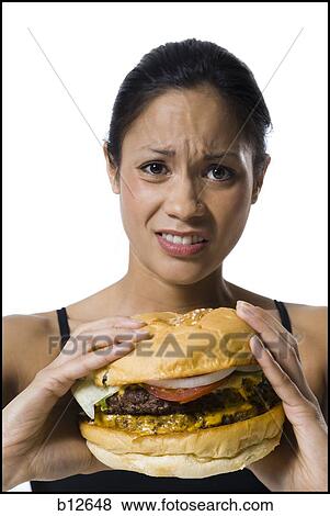 Stock Photo - Woman eating a supersized hamburger. Fotosearch
