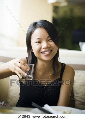 Stock Image - Woman eating at a Chinese food restaurant. Fotosearch