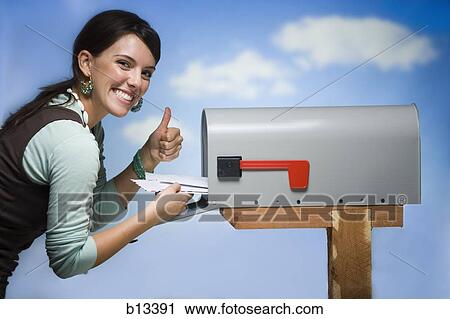 Stock Image - Woman getting mail from letterbox thumbs up. Fotosearch