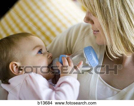 Woman holding baby with bottle View Large Photo Image Picture - Woman holding baby with bottle. Fotosearch