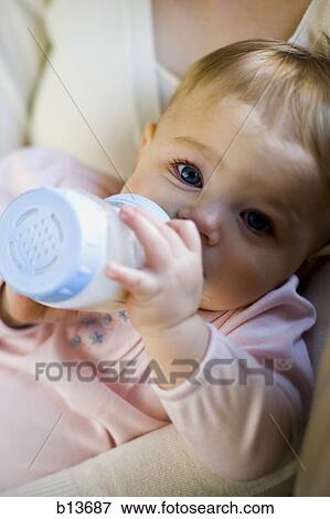 Stock Photo - Woman holding baby with bottle. Fotosearch