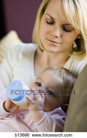 Stock Photograph - Woman holding baby with bottle. Fotosearch