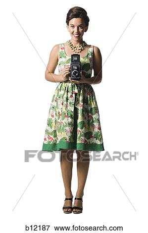 Stock Photo - Woman in floral dress holding antique camera. Fotosearch