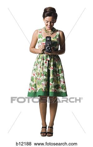 Woman in floral dress holding antique camera View Large Photo Image Stock Photo - Woman in floral dress holding antique camera. Fotosearch