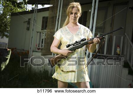 Stock Photograph - Woman in trailer park with a rifle. Fotosearch