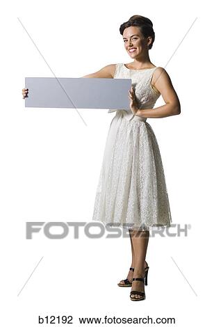 Stock Image - Woman in white dress holding a blank sign. Fotosearch