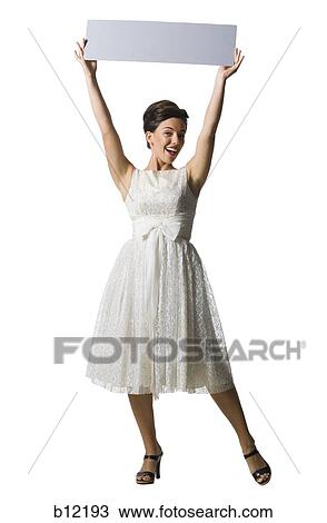 Stock Image - Woman in white dress holding a blank sign. Fotosearch