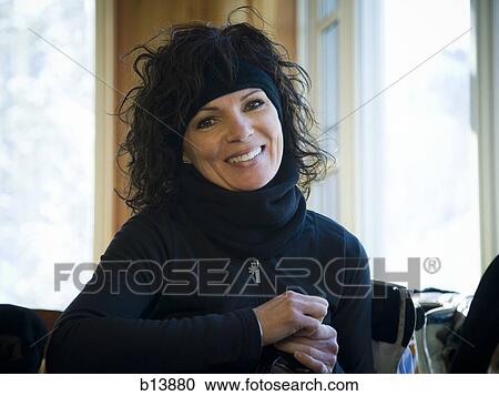 Stock Image - Woman indoors smiling in winter attire. Fotosearch