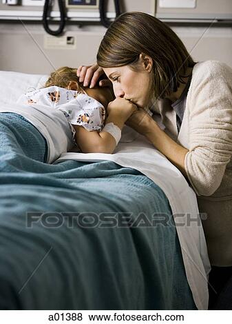 Stock Photo - Woman kissing hand of young girl in hospital. Fotosearch