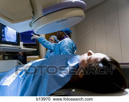 Woman on diagnostic bed with male and female technicians looking at monitors View Large Photo Image Stock Image - Woman on diagnostic bed with male and female technicians looking at monitors. Fotosearch