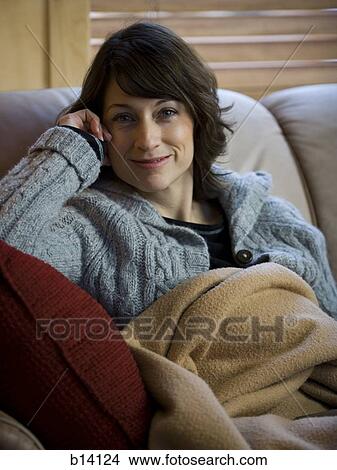 Woman on sofa with blanket smiling View Large Photo Image Picture - Woman on sofa with blanket smiling. Fotosearch