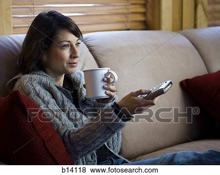 Woman on sofa with coffee mug and remote View Large Photo Image Stock Photo - Woman on sofa with coffee mug and remote. Fotosearch
