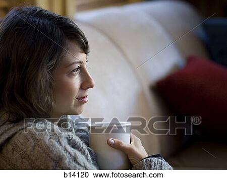 Stock Image - Woman on sofa with coffee mug. Fotosearch