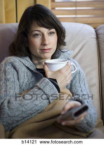Stock Image - Woman on sofa with coffee mug. Fotosearch