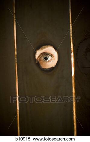 Stock Photography - Woman peeping through hole in fence. Fotosearch