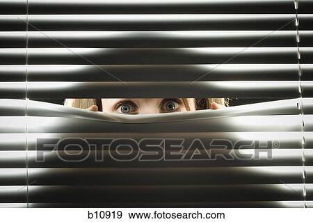 Stock Photo - Woman peeping through horizontal blinds. Fotosearch