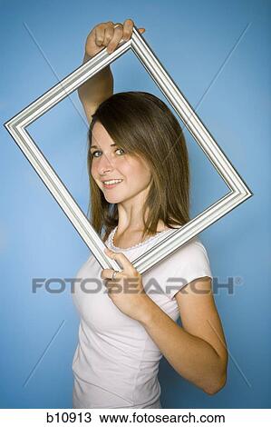 Stock Image - Woman posing with an empty picture frame. Fotosearch