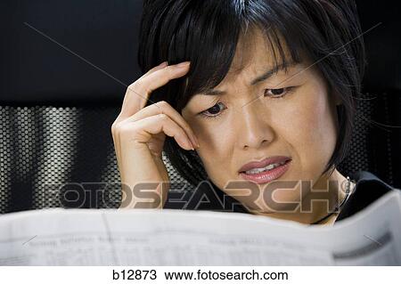 Stock Image - Woman reading financial pages of newspaper. Fotosearch