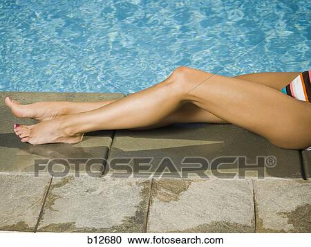 Stock Image - Woman relaxing by a swimming pool. Fotosearch