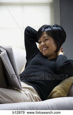 Woman relaxing on sofa and reading newspaper View Large Photo Image Stock Photo - Woman relaxing on sofa and reading newspaper. Fotosearch