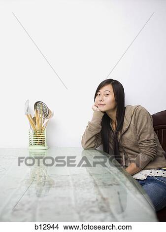 Woman sitting at a table with kitchen utensils View Large Photo Image Picture - Woman sitting at a table with kitchen utensils. Fotosearch