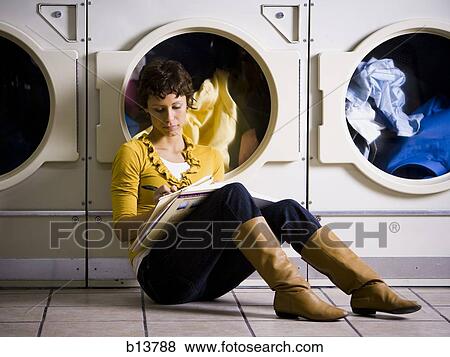 Woman sitting at Laundromat with books writing View Large Photo Image Stock Photo - Woman sitting at Laundromat with books writing. Fotosearch