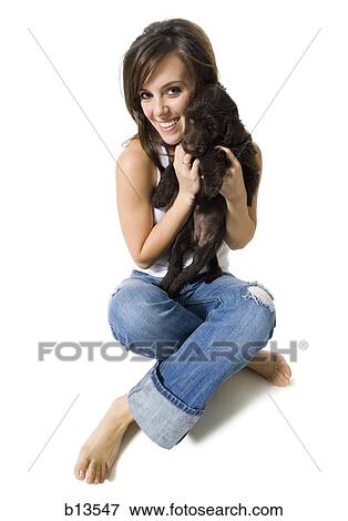 Stock Photo - Woman sitting cross legged with puppy. Fotosearch