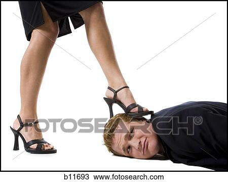 Stock Image - Woman stepping on man's face with heels. Fotosearch