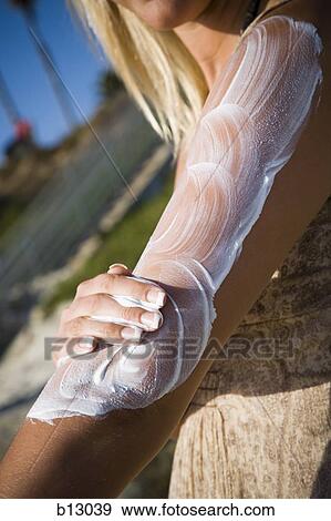 Stock Photo - Woman sunbathing and applying lotion. Fotosearch