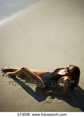 Stock Photograph - Woman sunbathing on beach. Fotosearch