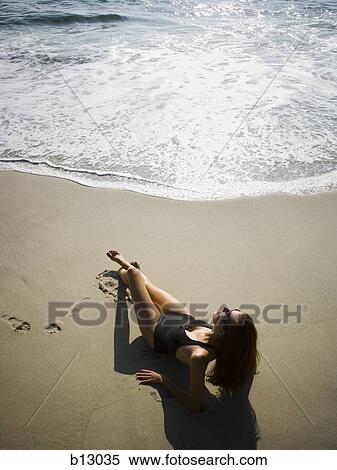 Stock Photography - Woman sunbathing on beach. Fotosearch
