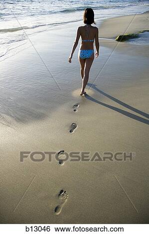 Woman walking on a beach leaving footprints in sand View Large Photo Image Stock Photograph - Woman walking on a beach leaving footprints in sand. Fotosearch