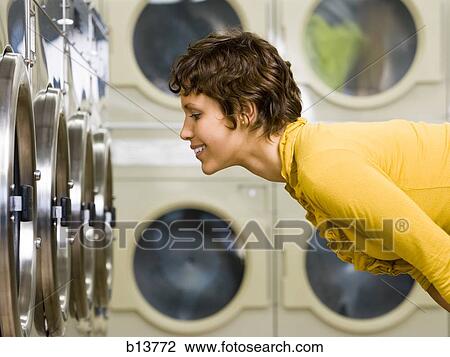 Woman watching clothes in dryer at Laundromat View Large Photo Image Stock Image - Woman watching clothes in dryer at Laundromat. Fotosearch