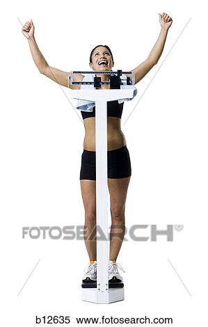 Stock Photography - Woman weighing herself on scale. Fotosearch