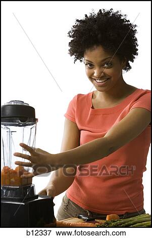 Stock Photo - Woman with carrots in a blender. Fotosearch