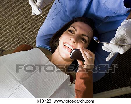 Stock Photo - Woman with dental hygienist talking on cell phone. Fotosearch