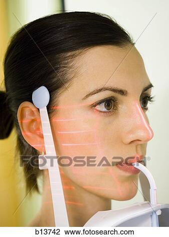 Stock Image - Woman with dental laser x-ray machine in mouth. Fotosearch